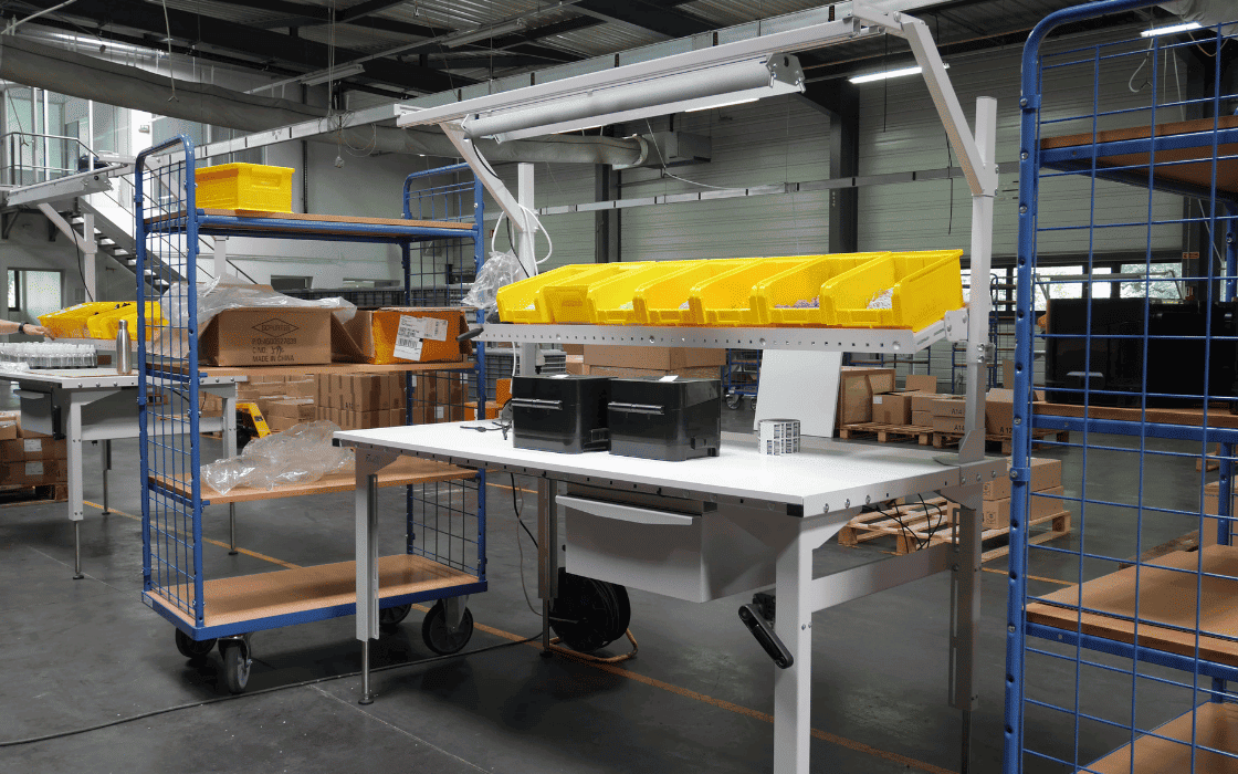 r&eacute;alisation d'une table avec accessoires r&eacute;glable en hauteur par manivelle avec des bacs &agrave; becs jaunes sur &eacute;tag&egrave;res dans un entrepot de production