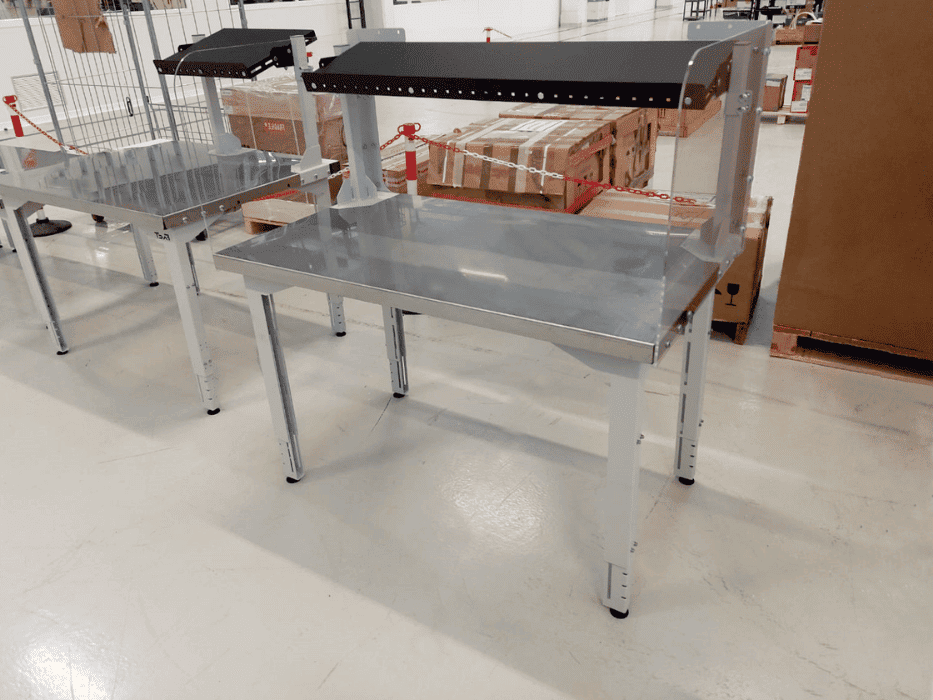r&eacute;alisation de tables avec un plateau inox ainsi qu'une vitre de plexiglas sur le cot&eacute; de la table dans un entrepot 